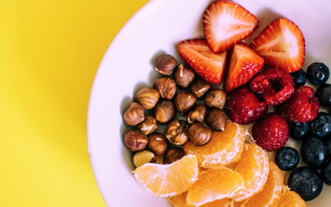 A plate that includes berries, nuts, and other fruits.